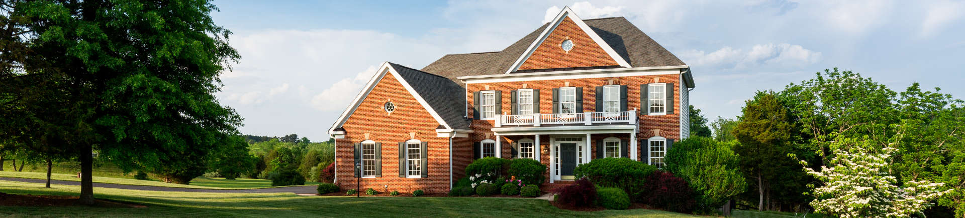 larage red-brick hose with manicured lawn and shaped shrubs