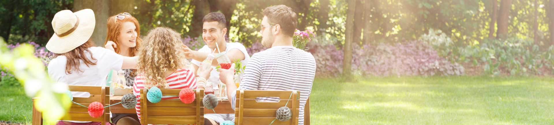 a group of young friend having lunch at a wooden table in the well-maintained garden