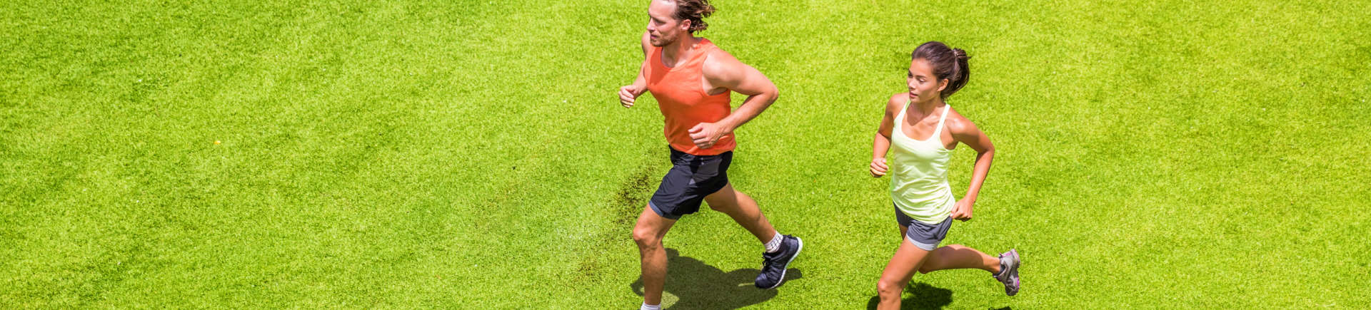 young sporty couple running across well-maintained lawn