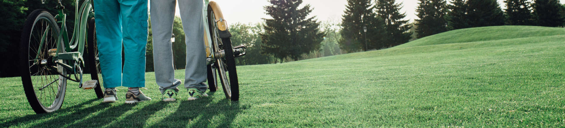 senior couple with their bicycles standing on grass and admiring views